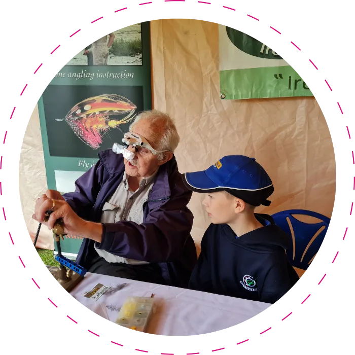 older man showing a younger boy how to fly tie for fishing